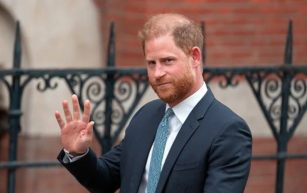 Чоловік у костюмі махає рукою на вулиці