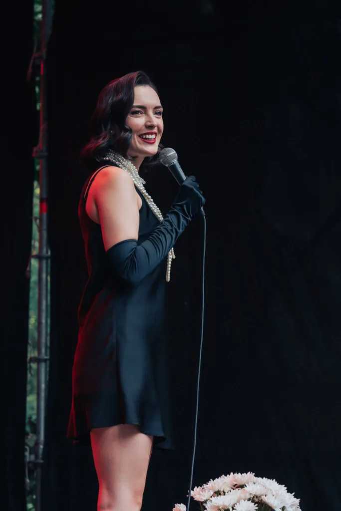 Жінка у чорній сукні співає на сцені