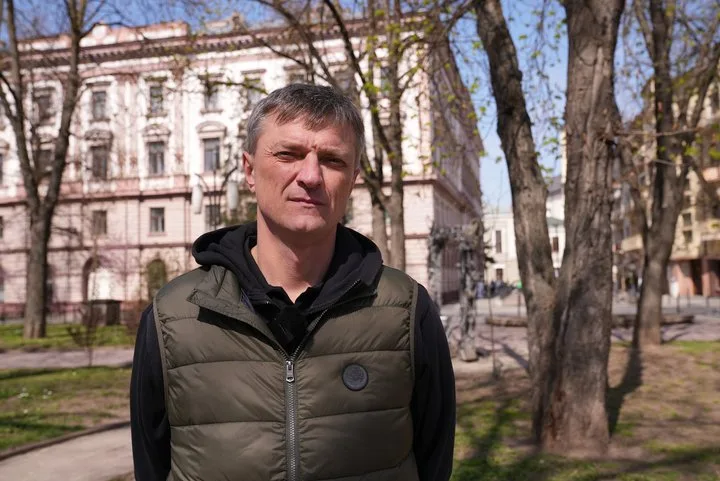 Чоловік стоїть у парку перед старою будівлею