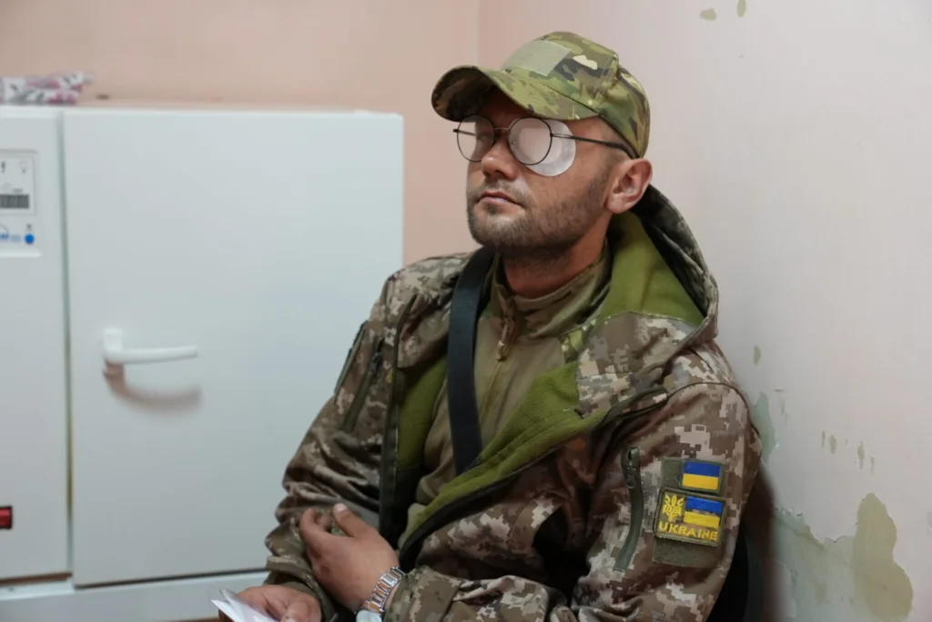 Український військовий у камуфляжі сидить у приміщенні