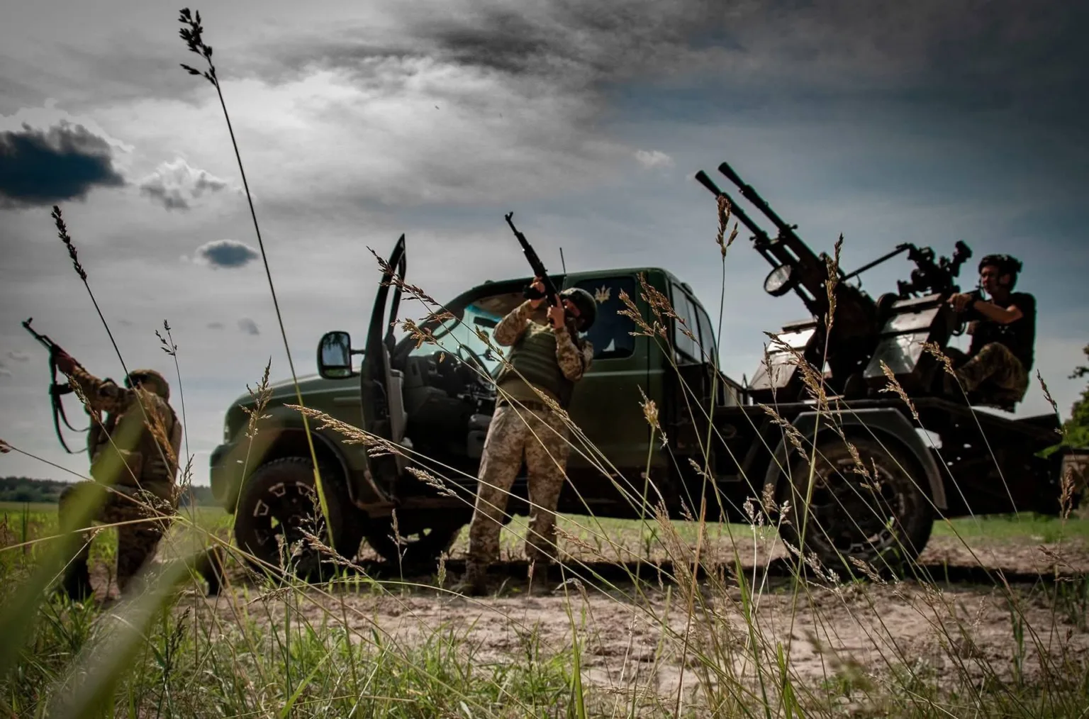 Військові біля вантажівки з гарматою на полі