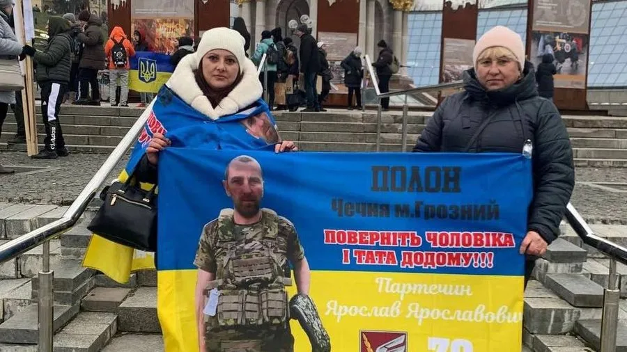 Жінки тримають плакат із фото військовослужбовця