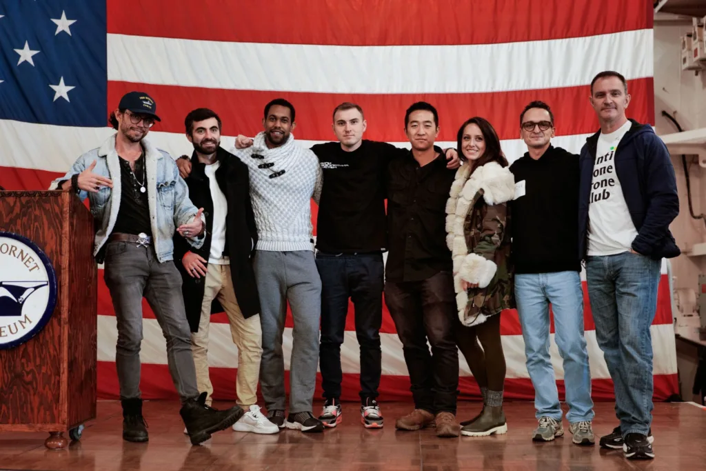 Група людей позує перед великим американським прапором