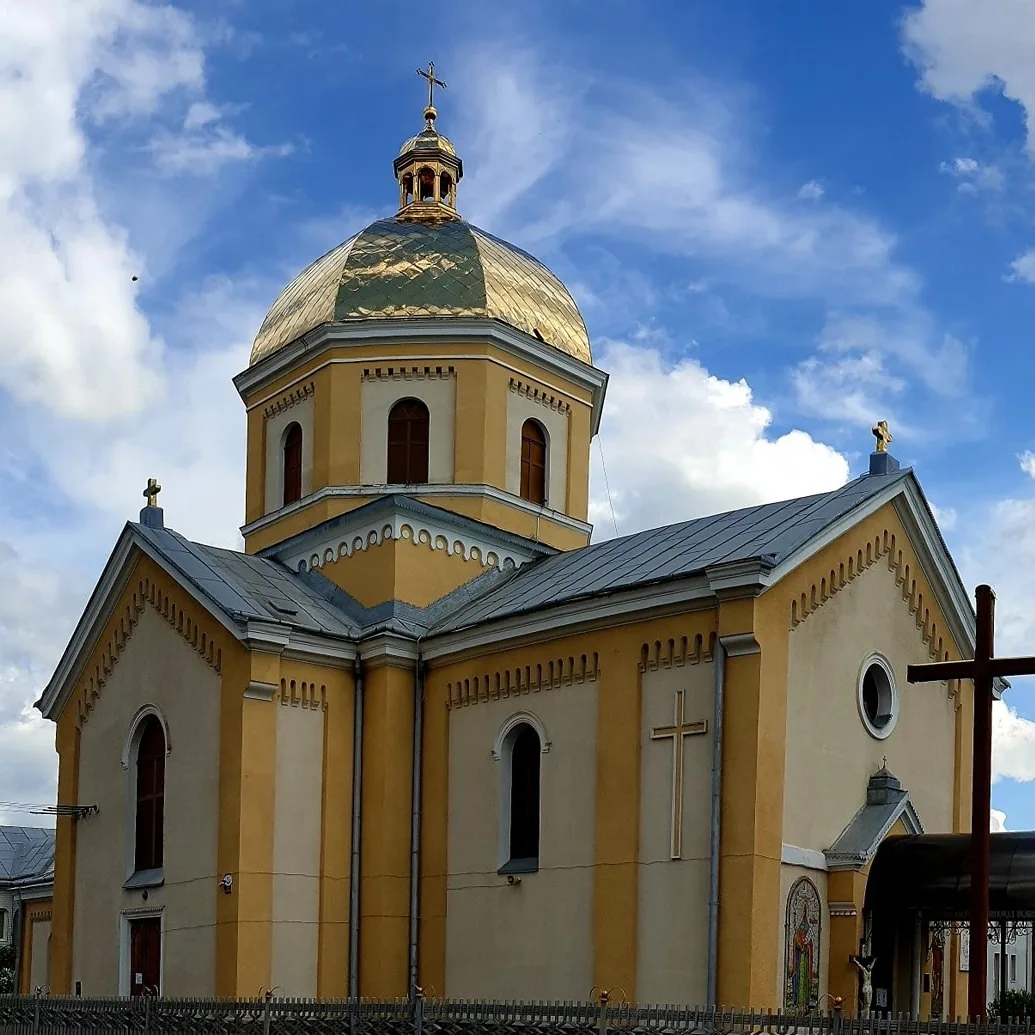 Жовта церква з золотою куполою під синім небом