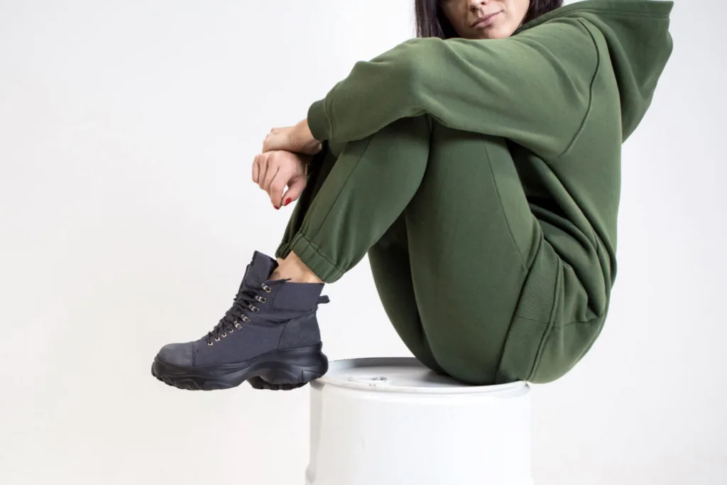 Жінка у зеленому спортивному костюмі та чорних черевиках