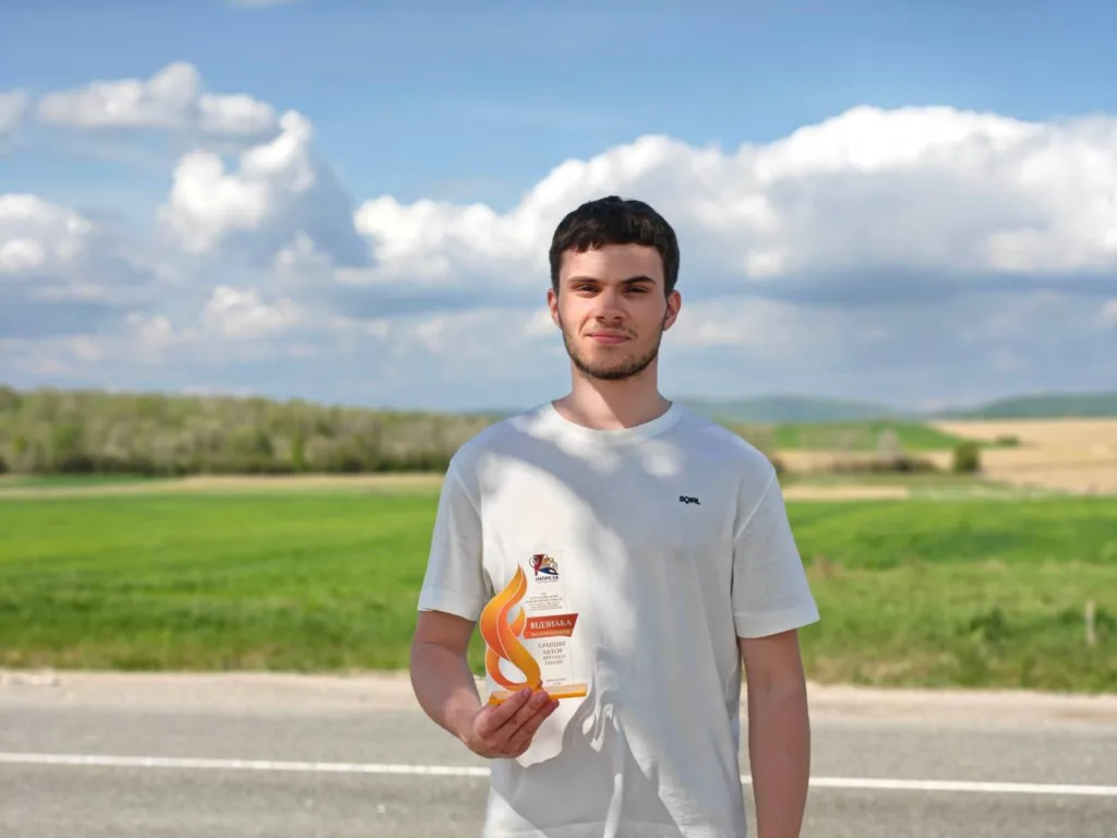 Молодий чоловік тримає нагороду на природі