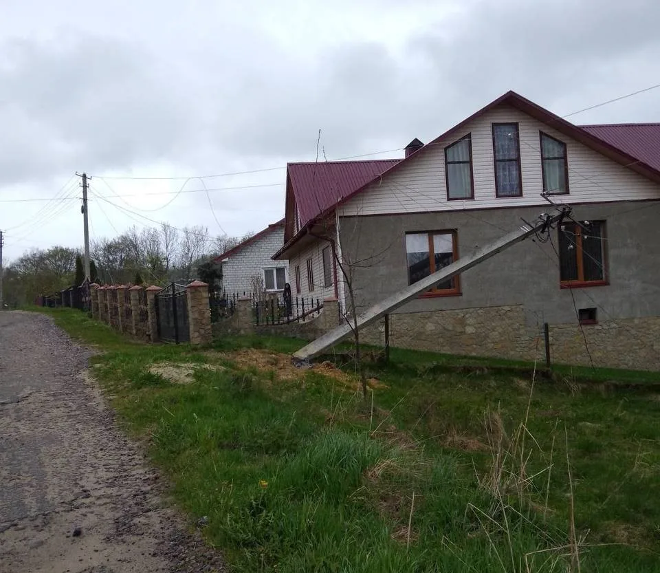 Похилений електричний стовп біля приватного будинку