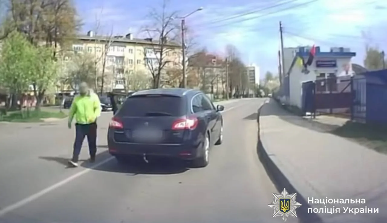 Пішохід переходить дорогу перед чорним автомобілем