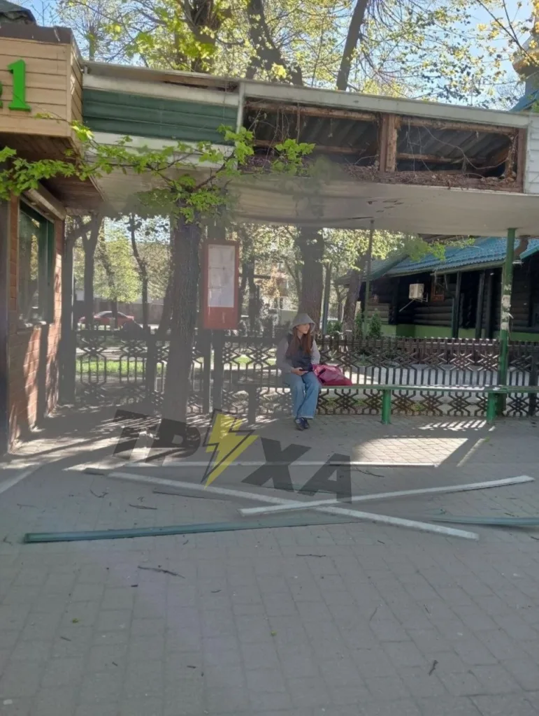 Жінка сидить на лавці біля зупинки