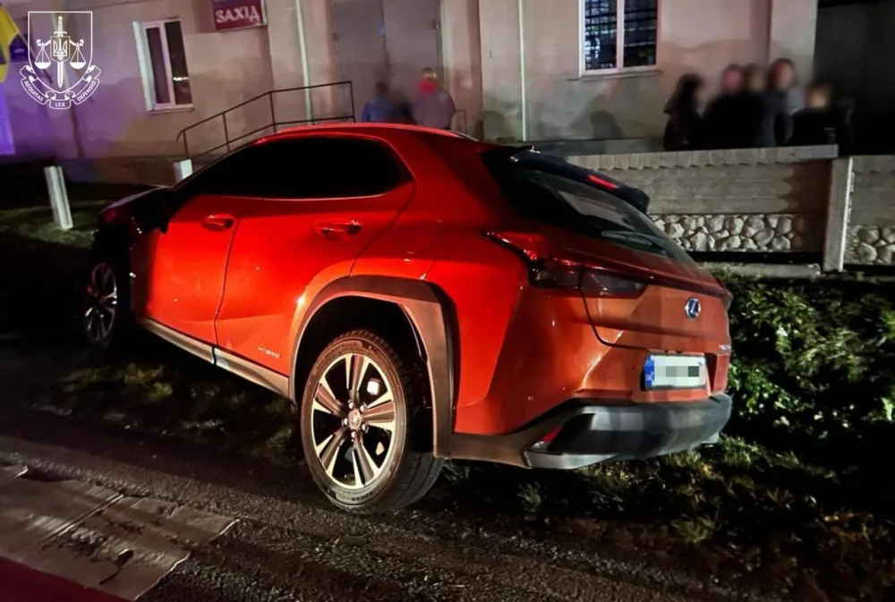 Червоний автомобіль Lexus біля будинку вночі