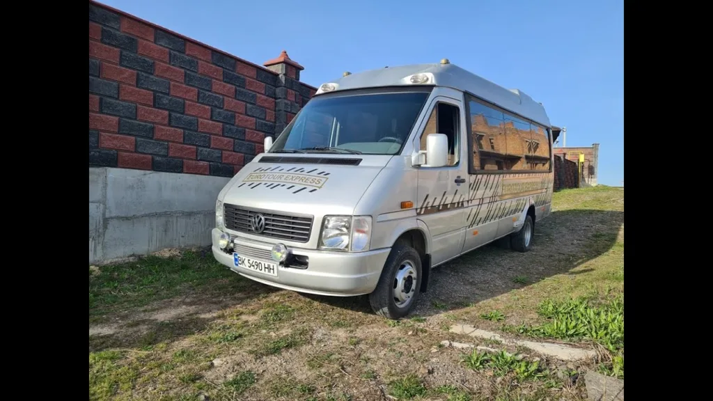 Сірий мікроавтобус Volkswagen біля цегляного паркану