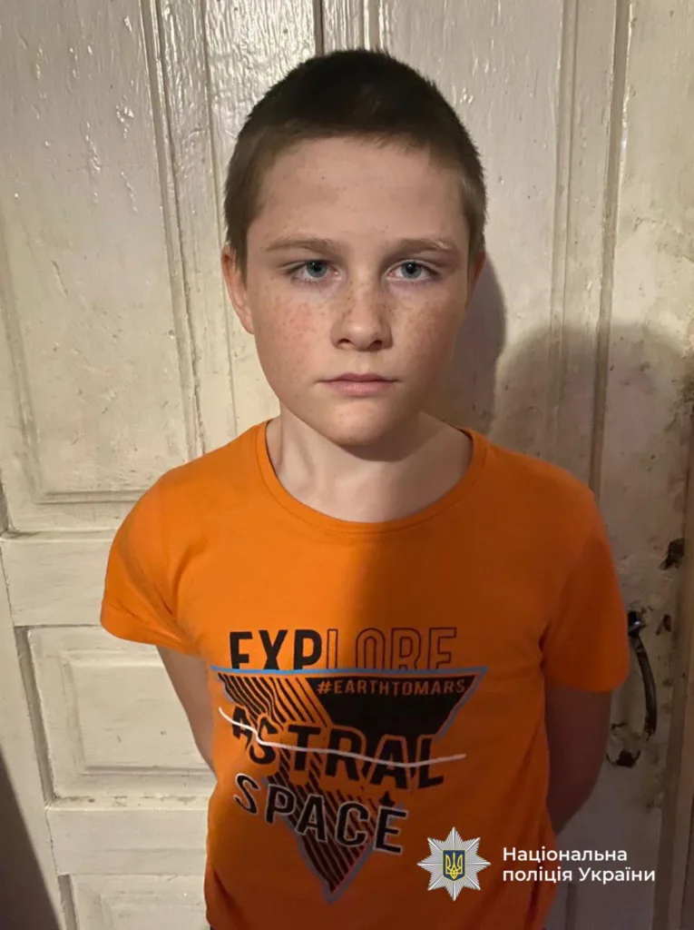 Хлопчик у помаранчевій футболці біля дерев'яних дверей