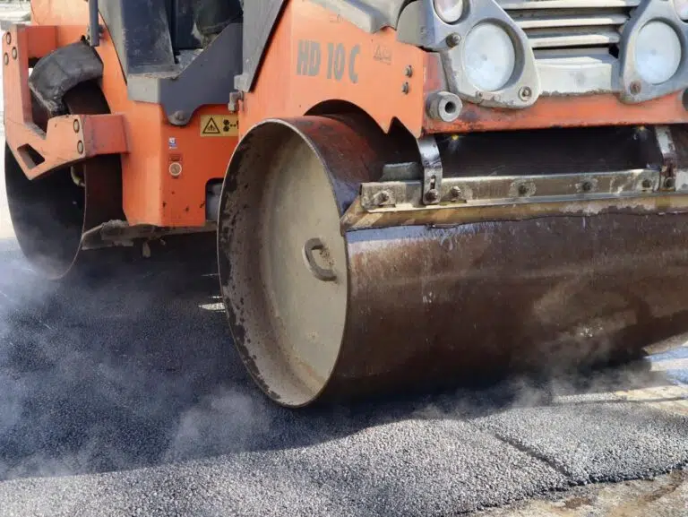 Каток ущільнює гарячий асфальт на дорозі