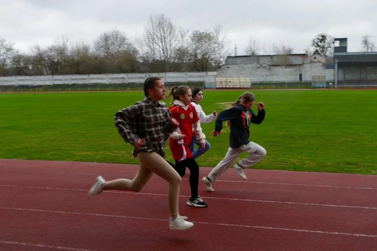 Діти біжать на біговій доріжці стадіону