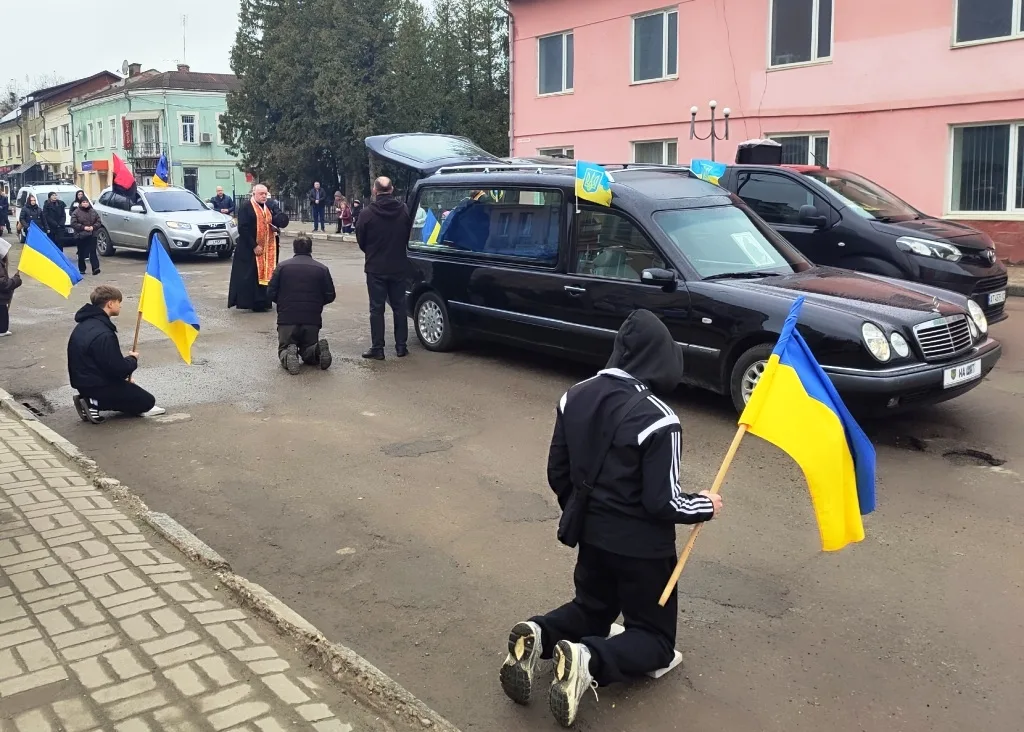 Люди з українськими прапорами на вулиці під час процесії