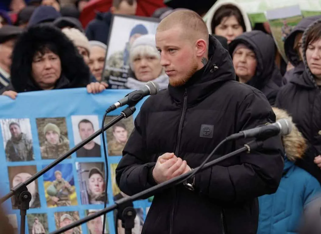 Чоловік виступає на мітингу перед людьми з плакатами
