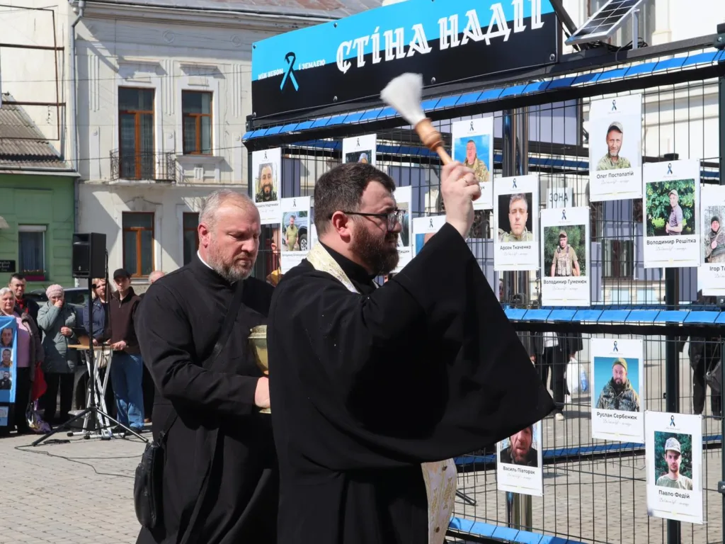 Священник освячує Стіну Надії з фото військових