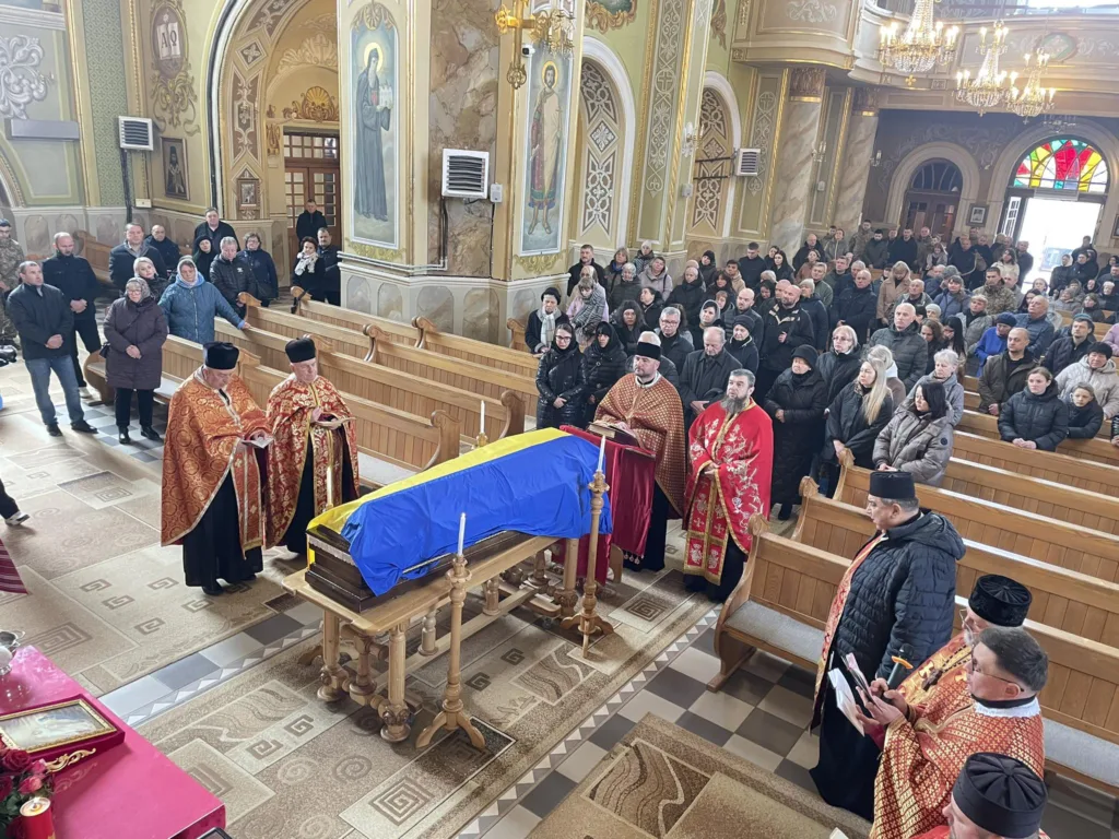 Похоронна служба в церкві з труною під прапором України