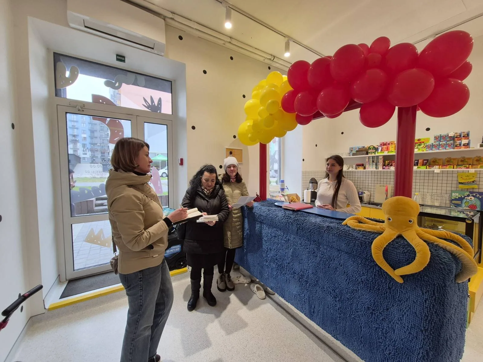Люди у дитячому магазині біля стійки з повітряними кулями