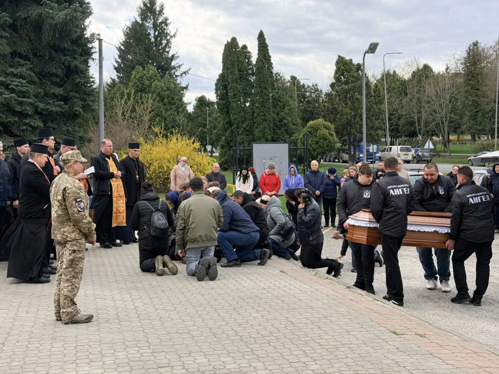 Прощання з військовим, священики та люди на колінах