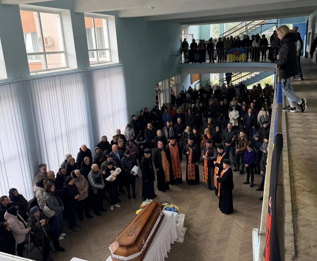 Прощання з військовим у приміщенні, люди моляться