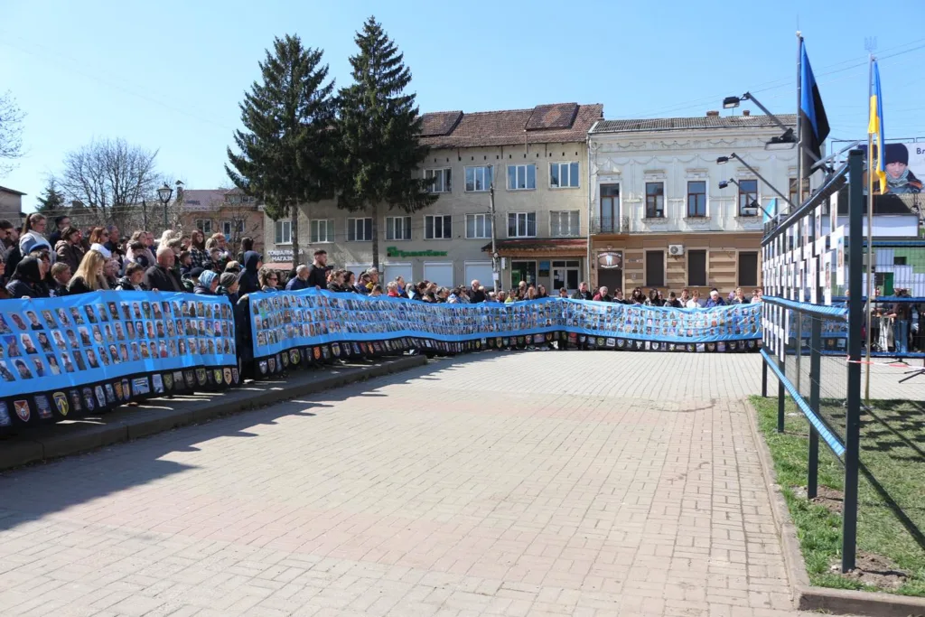 Люди тримають банер із фото героїв на площі