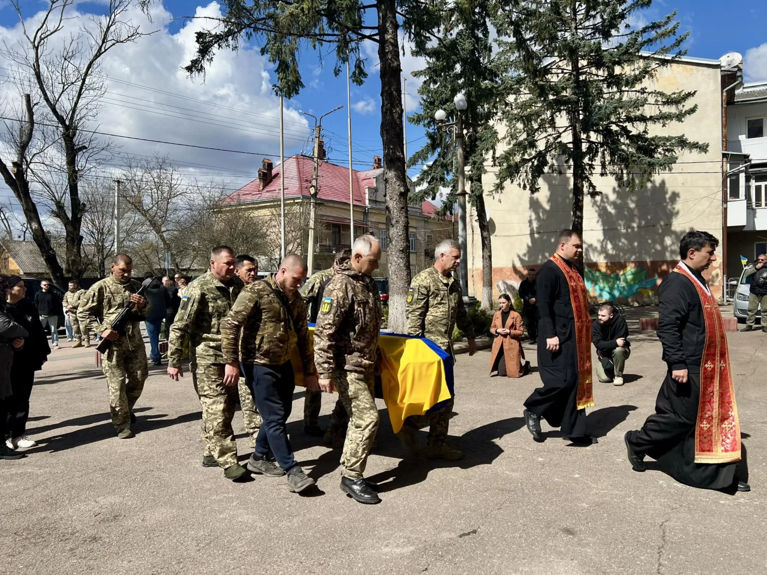 Військові несуть труну, накриту українським прапором