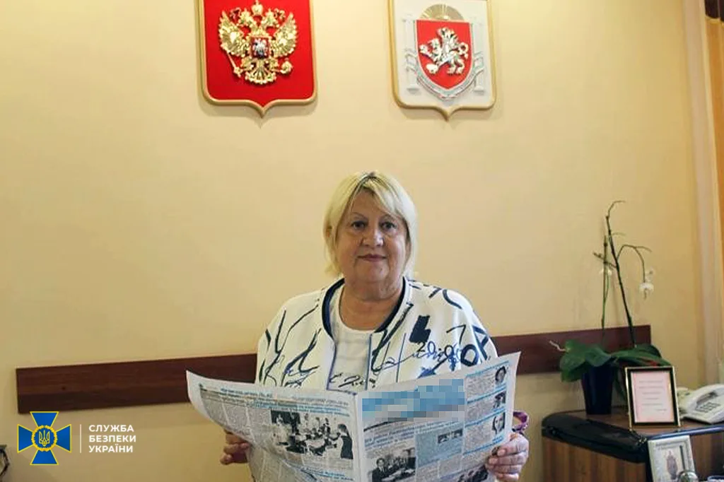 Жінка тримає газету в офісі з гербами