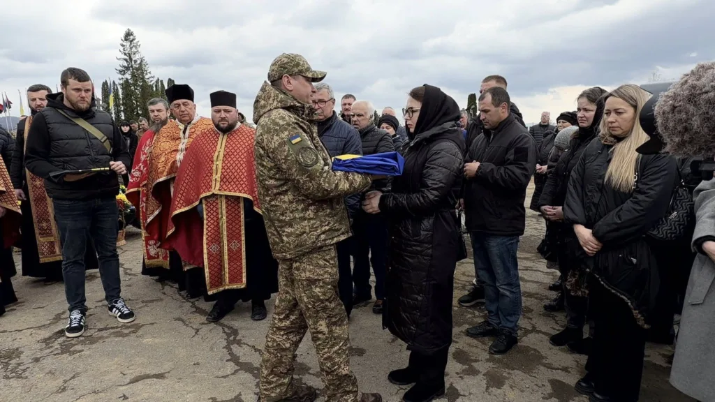 Військовий передає прапор під час похорону військового