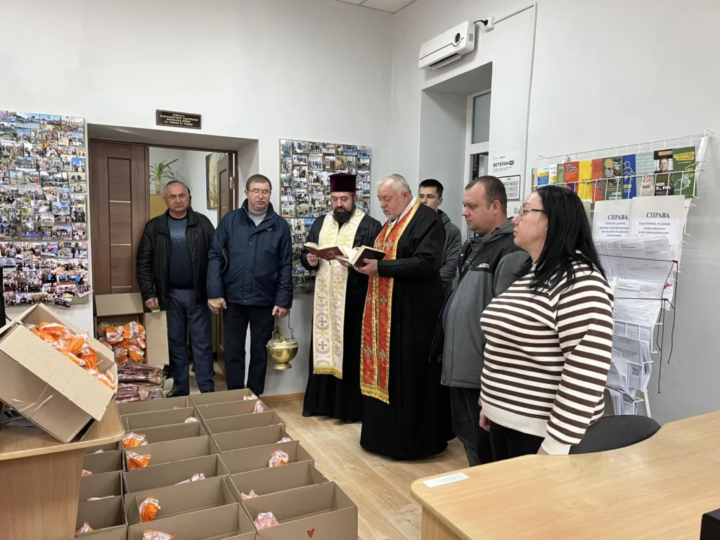 Священник благословляє гуманітарну допомогу у приміщенні