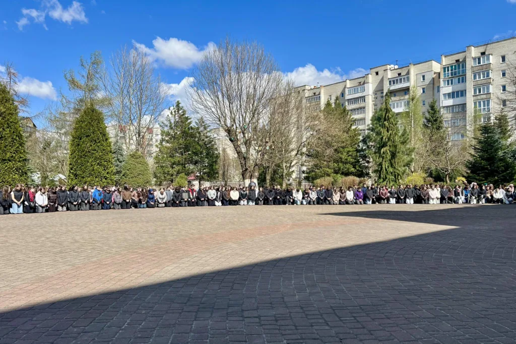 Люди стоять на площі перед будинками навесні