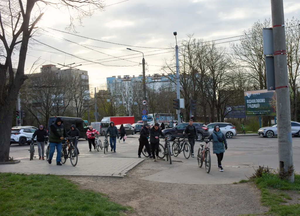 Люди переходять дорогу з велосипедами у місті