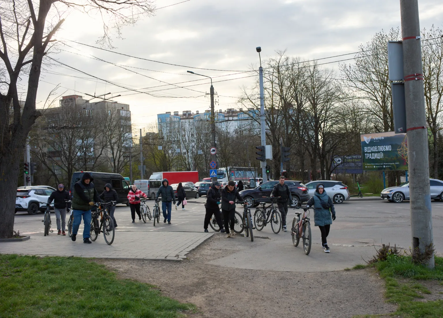 Люди переходять дорогу з велосипедами у місті