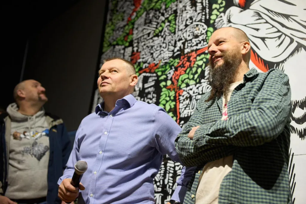 Троє чоловіків на події перед яскравим муралом