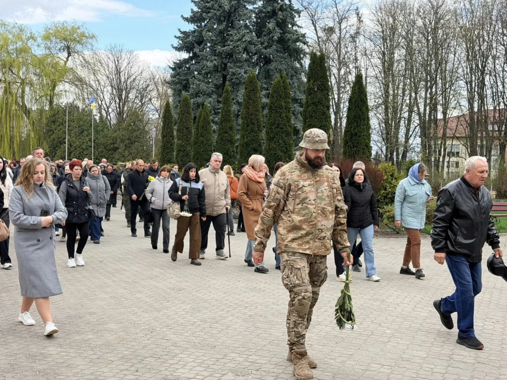 Люди йдуть з квітами на вшанування пам'яті