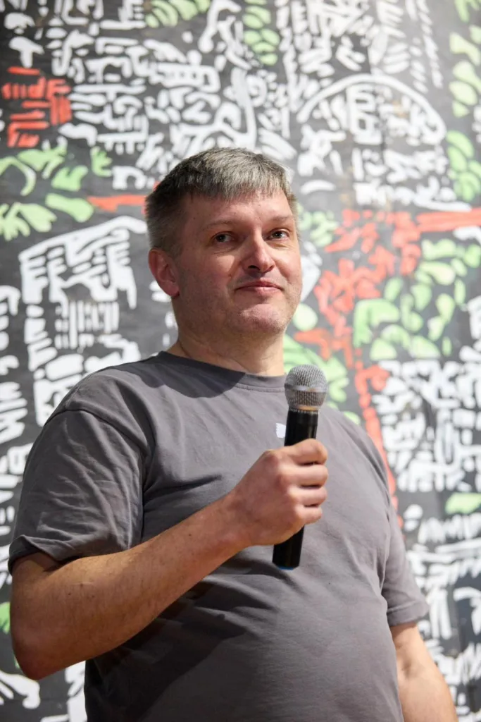 Чоловік тримає мікрофон перед кольоровим фоном