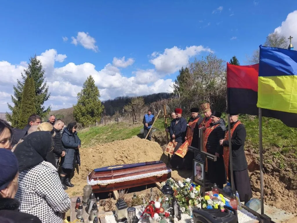 Похоронна церемонія з українськими прапорами на кладовищі