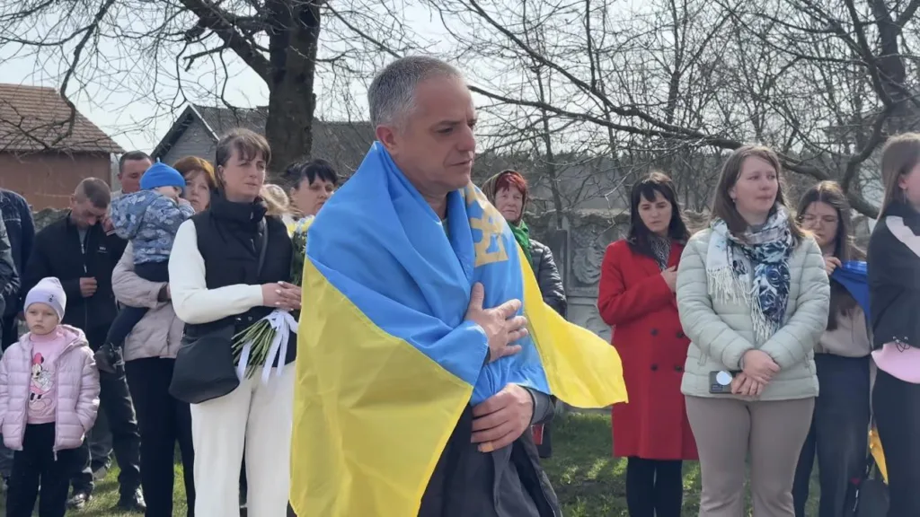 Люди на церемонії з українським прапором