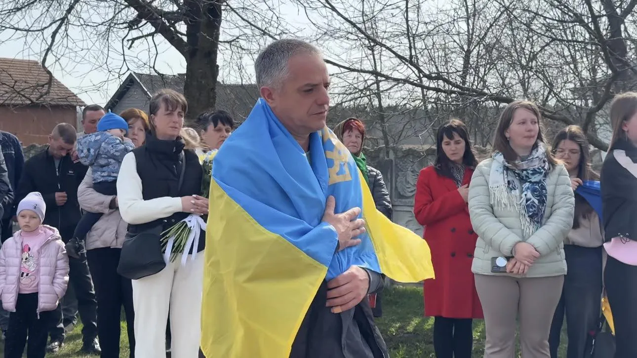 Люди на церемонії з українським прапором