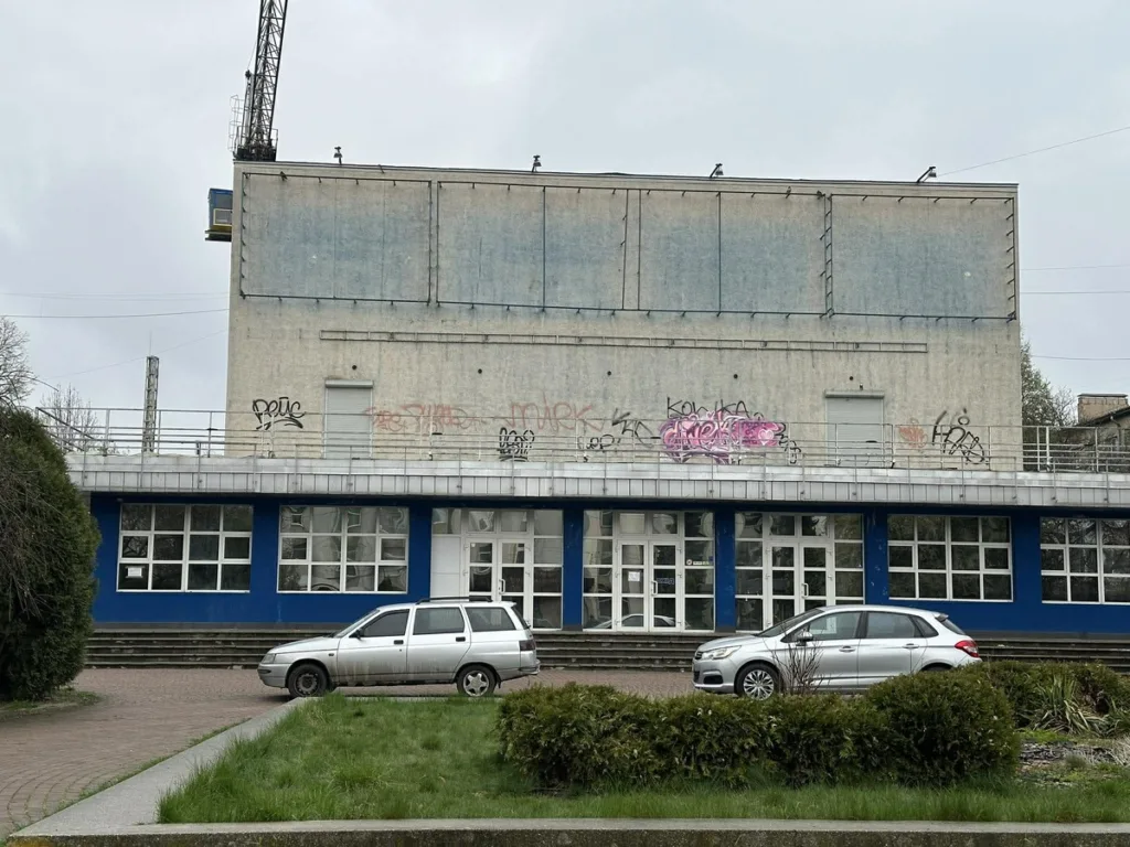 Занедбана будівля з графіті та припаркованими авто