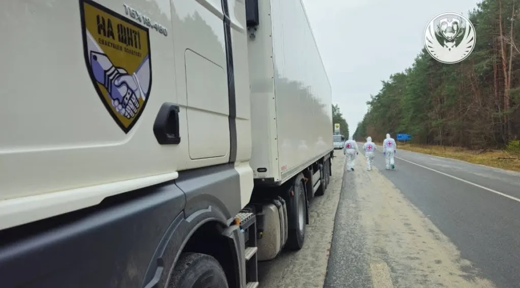 Вантажівка на дорозі, люди у захисних костюмах