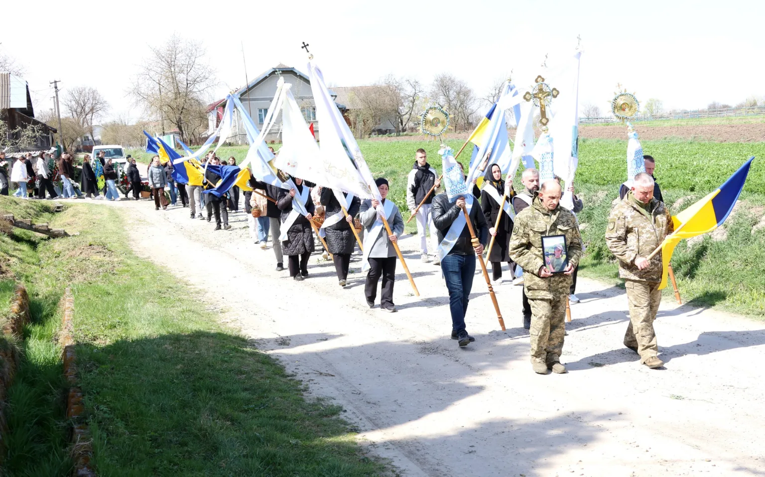 Похоронна процесія з прапорами в українському селі