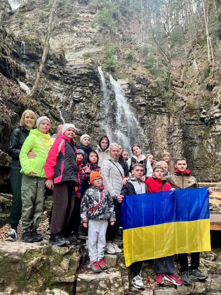 Група людей з українським прапором біля водоспаду