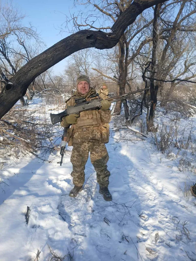 Військовий у зимовому лісі тримає зброю