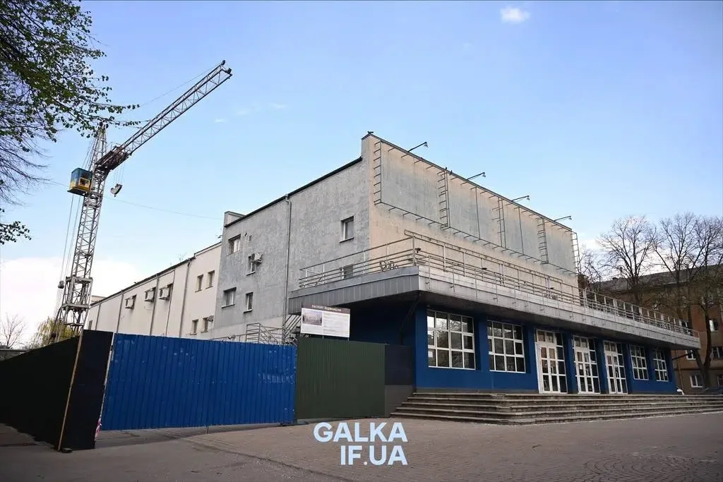 Реконструкція сірого будинку з краном поруч