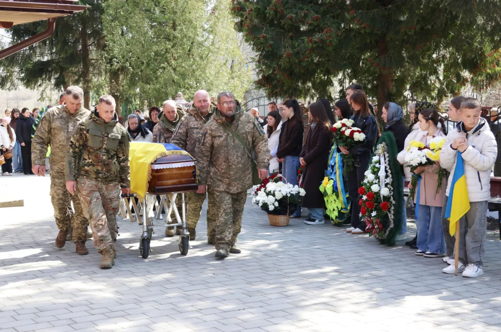 Військові несуть труну, люди тримають квіти