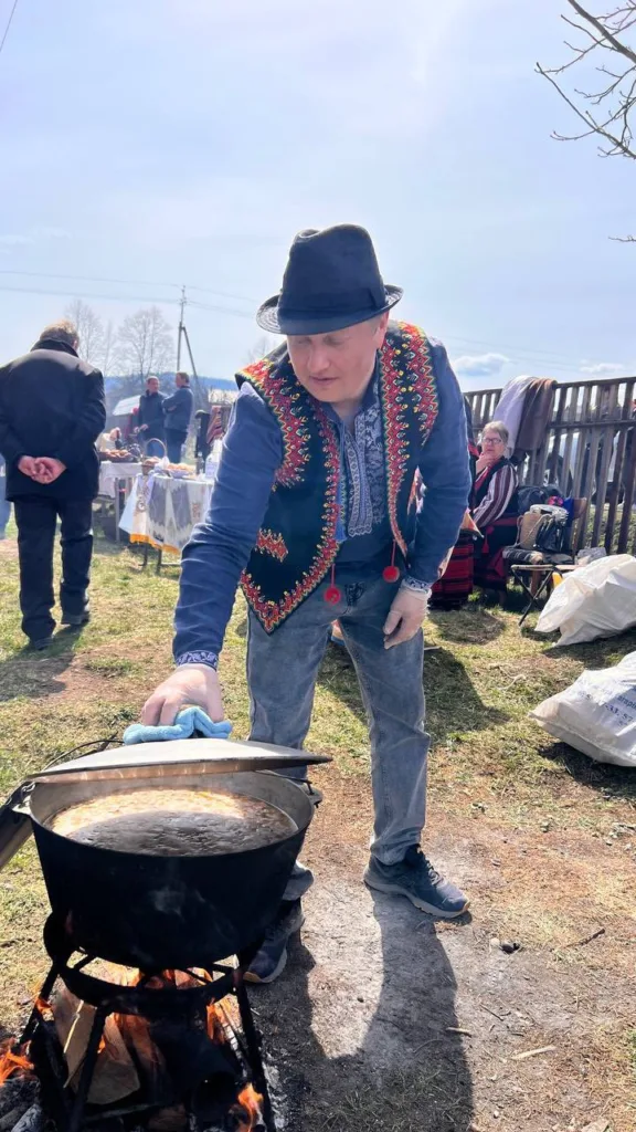 Чоловік готує страву в казані на вогні