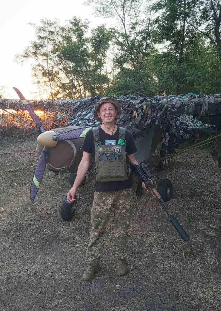 Військовий стоїть перед замаскованим літаком