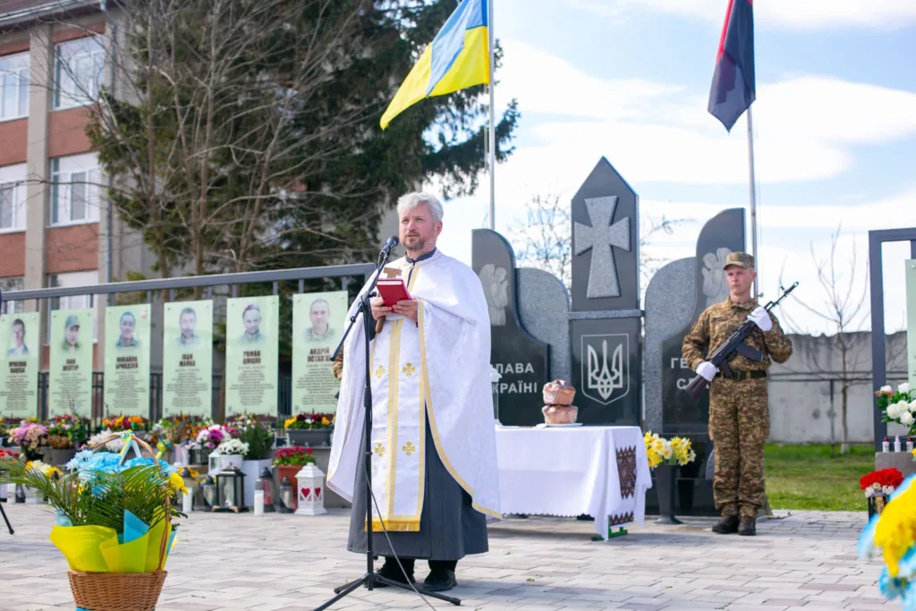 Священник і військовий на церемонії біля меморіалу