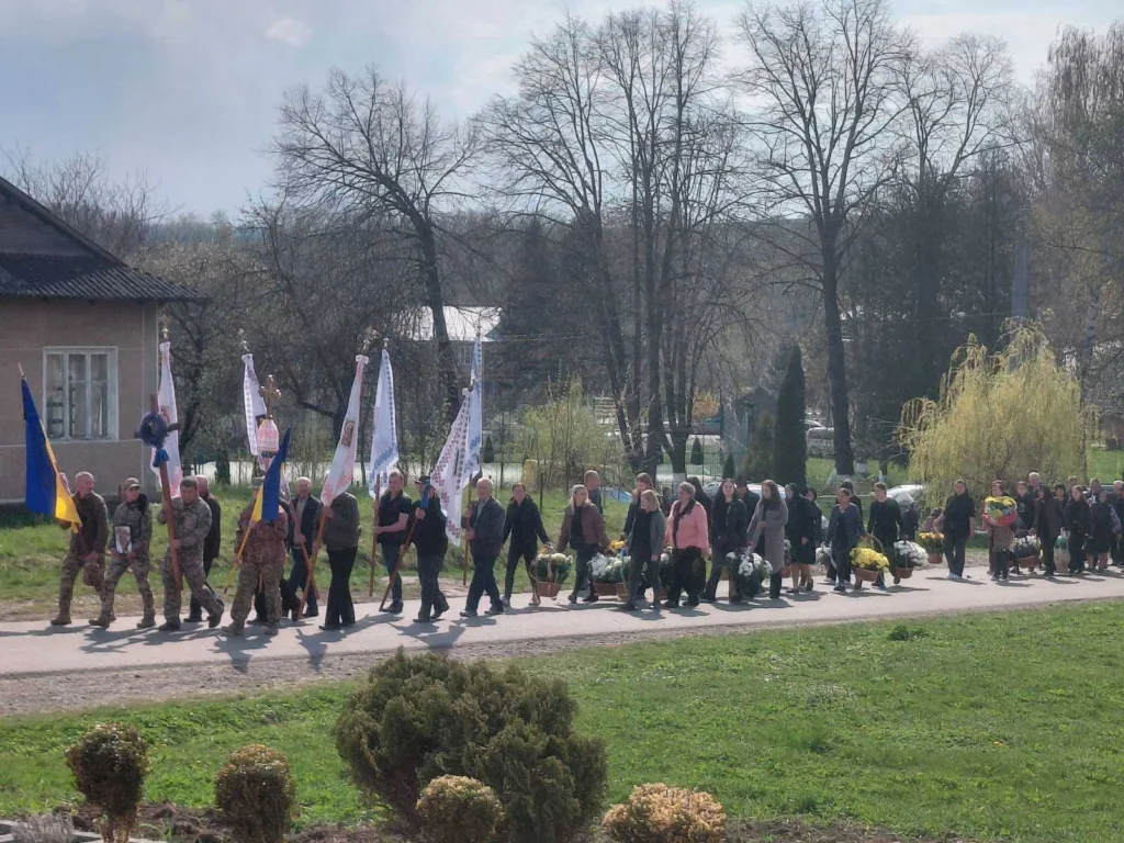 Похоронна процесія з прапорами та квітами на вулиці